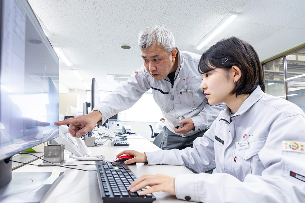熟練の技術者が、若手社員に設計ノウハウを伝承している風景
